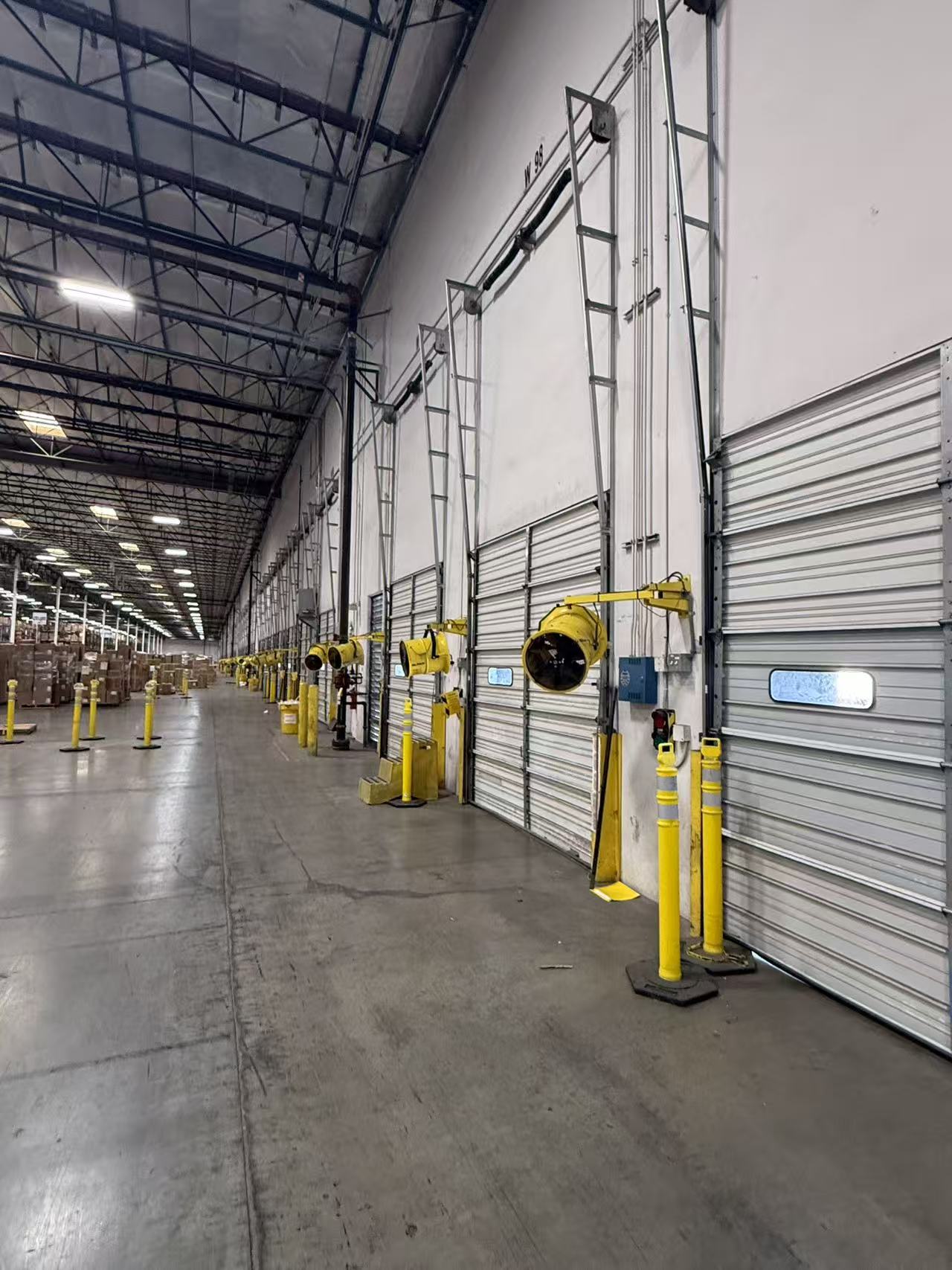 Row of high-bay dock doors with fans, lights, and safety equipment at a Redlands 3PL facility